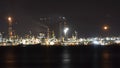 Oil refinery plant at night. Long exposure of factory lights reflection on sea. Noise and grain included Royalty Free Stock Photo