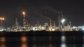 Oil refinery plant at night. Long exposure of factory lights reflection on sea. Noise and grain included Royalty Free Stock Photo