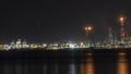 Oil refinery plant at night. Long exposure of factory lights reflection on sea. Noise and grain included Royalty Free Stock Photo