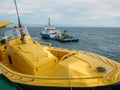 Oil research and exploration seismic vessel or ship in sea and yellow boat at another ship on foreground