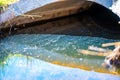 Oil sheen on contaminated storm water runoff coming out of a concrete culvert Royalty Free Stock Photo