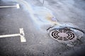 An oil slick of gasoline or oil on an asphalt road flows into a storm drain Royalty Free Stock Photo