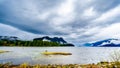 Oil slick on Pitt Lake under a dark cloudy sky with rain clouds hanging around the Mountains Royalty Free Stock Photo
