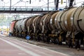 Oil tanks being pulled by train through railway station delivering crude oil fuel