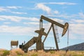 Oil Well Against Mountains and Blue Cloudy Sky