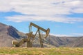 Oil Well Against Mountains and Blue Cloudy Sky