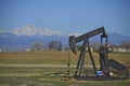 Oil well, pump jack with snow capped mountains