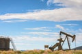 Oil Well And Tank Against Mountains and Blue Cloudy Sky Royalty Free Stock Photo