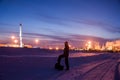 Oil worker in oilfield. Pump jack and engineer on a winter sunset sky background. Western Siberia.