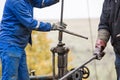 Oil workers check oil pump. Roustabouts doing dirty and dangerous work