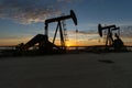 Oilfield pump jacks silhouetted against a morning sunrise