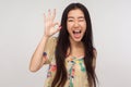 Ok I got it! Playful delighted asian girl with brunette hair in summer blouse winking joyfully and showing okay gesture