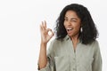 Okay I got it. Optimistic confident and carefree chill african american female coworker in grey stylish shirt winking