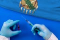 Hands of doctor holding syringe and coronavirus COVID-19 vial vaccine on flag Oklahoma