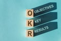 OKR - acronym from wooden blocks with letters, Objectives and Key Results OKR concept, blue background