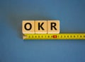 OKR, objectives and key results symbol. The word OKR, objectives and key results on cubes arranged behind the ruler on beautiful