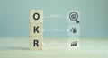 OKR text Objectives, Key and Results wooden cube block on grey background. Business target and drive business and performance. F