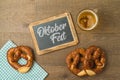 Oktoberfest party concept with pretzel, beer glass and chalkboard over wooden background. Top view, flat lay