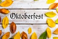 Oktoberfest sign and colorful autumn leaves. White wooden backgr Royalty Free Stock Photo