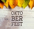 Oktoberfest sign and colorful autumn leaves. White wooden background Royalty Free Stock Photo