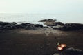 tropical dream paradise seascape of the pacific ocean from the shore with rocks and volcanic black sand and an open coconut Royalty Free Stock Photo