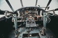 An old, abandoned airplane cockpit with handlebars and cranks