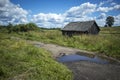 Old abandoned barn and country road with puddle Royalty Free Stock Photo