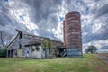 Old abandoned barn with silo under storm clouds Royalty Free Stock Photo