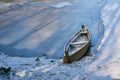 Old abandoned blue wooden broken boat under white snow on beach, lake covered by snow and foot traces, panoramic view of Royalty Free Stock Photo