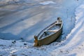 Old abandoned blue wooden broken boat under white snow on beach, lake covered by snow and foot traces, panoramic view of Royalty Free Stock Photo
