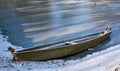 Old abandoned blue wooden broken boat under white snow on beach, lake covered by snow and foot traces, panoramic view of Royalty Free Stock Photo