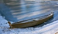 Old abandoned blue wooden broken boat under white snow on beach, lake covered by snow and foot traces, panoramic view of Royalty Free Stock Photo