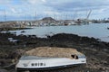 Old abandoned boat on the coast. Yacht pier at the background Corralejo, Fuerteventura, Spain