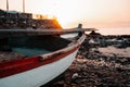 Old abandoned boat with rusted and chipped red and white paint, on a rocky beach at early morning sunrise golden hour Royalty Free Stock Photo