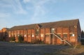 Old abandoned brick factory building with boarded up windows and steel staircase overgrown with weeds in leeds england