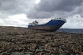 Old abandoned broken ship on the stoned coast sea side. cloudy sky storm time Royalty Free Stock Photo