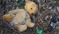 The old abandoned brown teddy bear toy is thrown into the garbage dump, nobody needs it and therefore cries Royalty Free Stock Photo