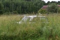 old abandoned car in the grass in forest. rural peaceful landscape. stolen and hidden car