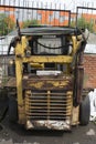 Old abandoned damaged rusty yellow mini loader tractor vertical close up back view Royalty Free Stock Photo