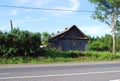 An old abandoned dilapidated village house near the road on a Sunny summer day. Russian provinces.