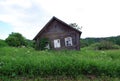 An old abandoned dilapidated village house near the road on a Sunny summer day. Russian provinces. Royalty Free Stock Photo