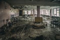 Old abandoned dining room in a children`s boarding house. Broken chairs. Withered plants. Sunlight in the windows