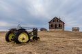 Old abandoned farmhouse overlooking a vintage tractor on the prairies in Saskatchewan