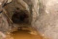 Old abandoned gold mine underground tunnel with rusty water lake. Dangerous tunnel full of dirt and rusty equipment. Royalty Free Stock Photo