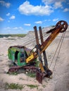 Old and abandoned green large excavator with heavy yellow shovel in limestone quarry. Rusty technique. Front view. Sunny summer Royalty Free Stock Photo
