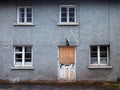 Old abandoned grey derelict house on a residential street with dirty broken windows and a boarded up door Royalty Free Stock Photo