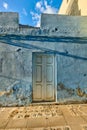 Old abandoned house or home with a weathered blue wall and wooden door. Vintage and aged residential building built in a Royalty Free Stock Photo