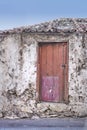 Old abandoned house or home with a weathered stone wall and red wooden door. Vintage and aged residential building built Royalty Free Stock Photo