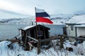 old abandoned house with a Russian flag on the shore of the Barents Sea in the Arctic Ocean. The village of Teriberka Kola Royalty Free Stock Photo