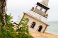 The old abandoned house on the shore falls into the sea. The destroyed tower heavily leaned over sand. The wooden building Royalty Free Stock Photo